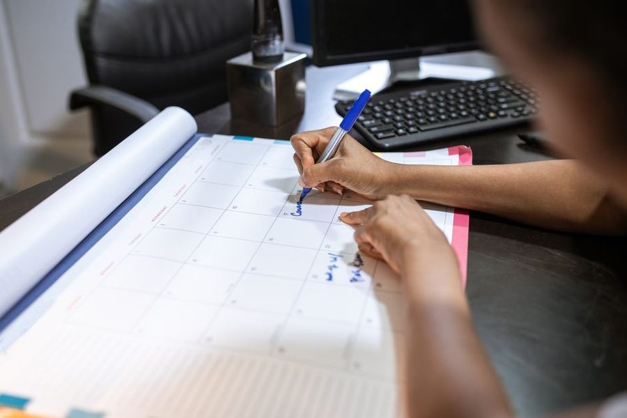 Mulher anotando uma data em um calendário de mesa