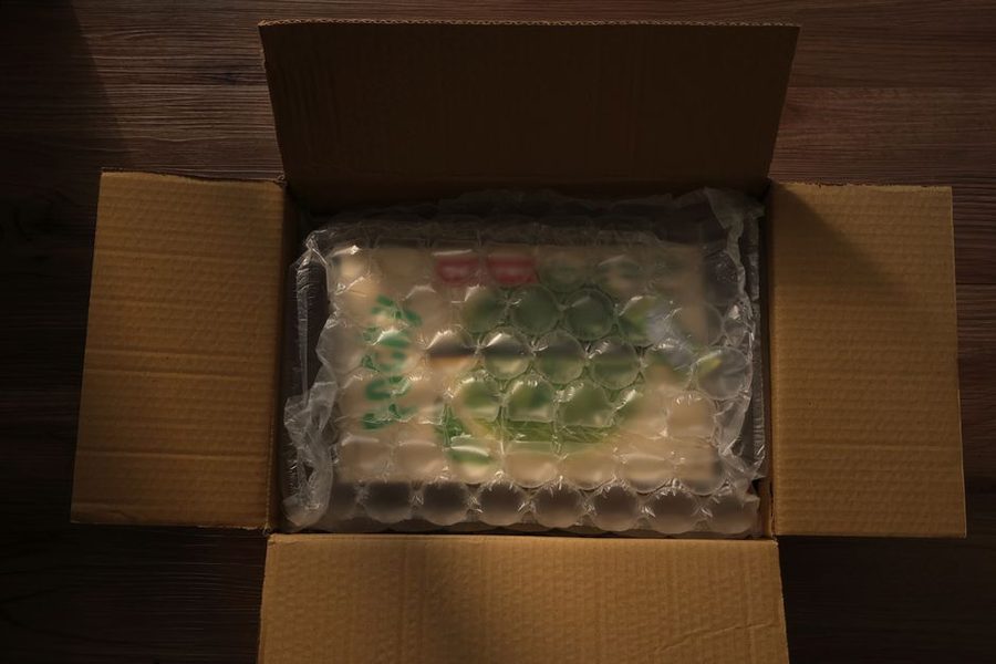 Caixa de papelão aberta com o produto envolto em plástico bolha